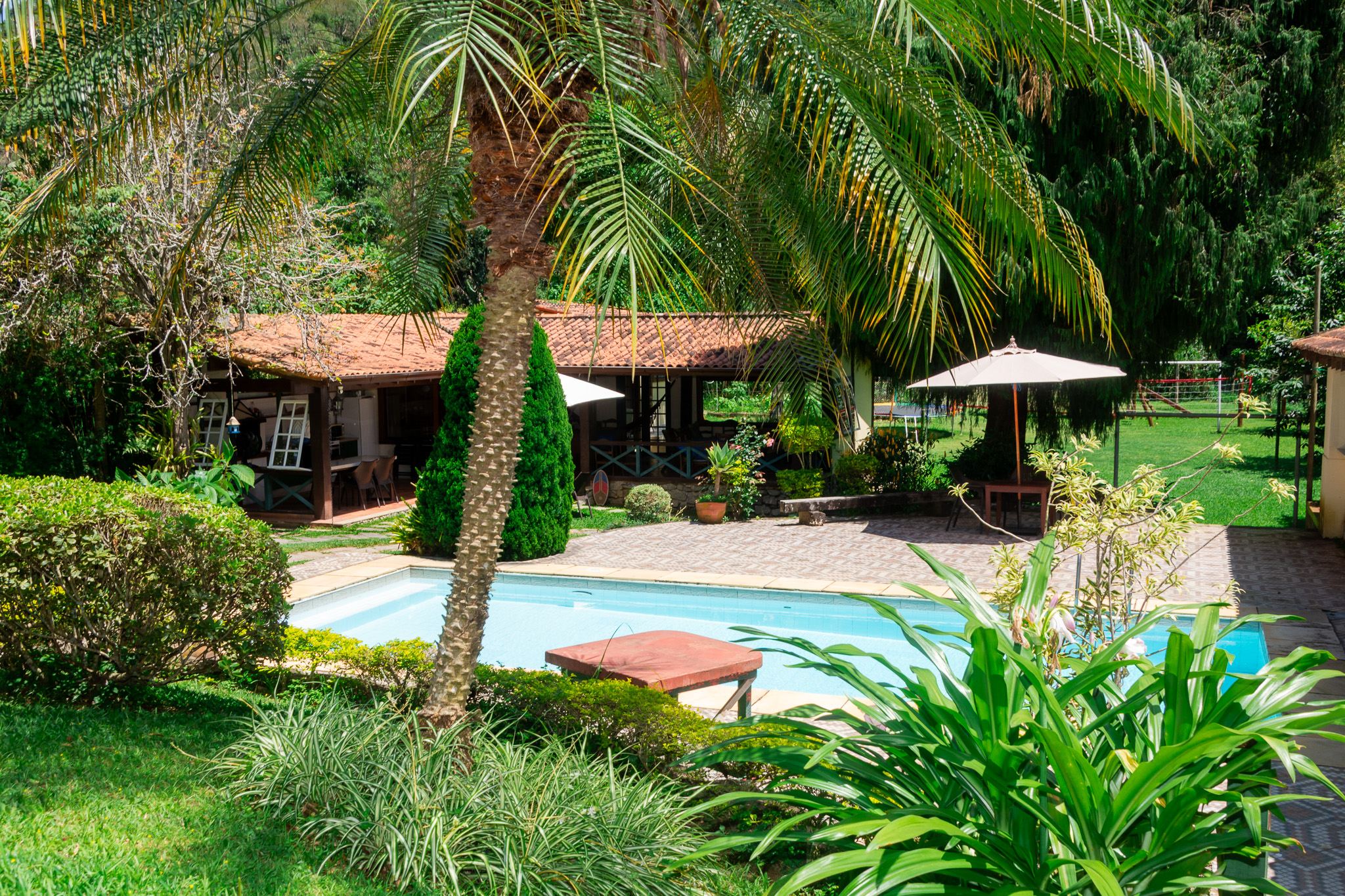 Jardim da Casa do Vale com palmeiras, gramado e piscina